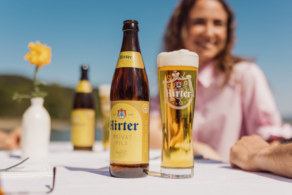 Kisten Hirter Bier Hirter Privatpils im Glas neben Flasche